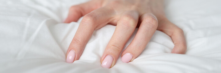 A woman's hand is squeezing a blanket on the bed