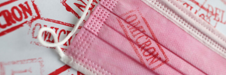 Red omicron stamp on a pink mask, close-up