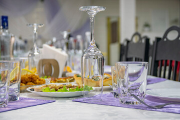 On festive banquet table there are plates with appetizers, cutlery and wine glasses. Beautifully decorated holiday table.