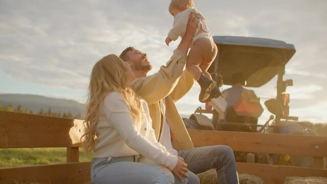Father picks up daughter in the air, golden light, tractor ride