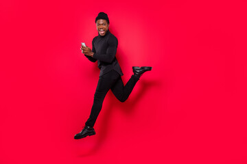Fototapeta na wymiar Full length body size view of handsome trendy cheery guy jumping using device isolated over vivid red color background