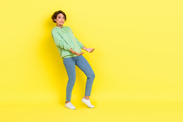 Fototapeta premium Full length photo of surprised funky lady wear green hoodie holding arms heavy empty space isolated yellow color background