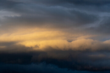 Dark cloud before raining storm and have the orange cloud that reflect light from sunset as background