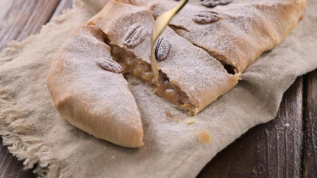 Strudel with apple. A typical sweet pastry in northern Italy, in Trento. Pie twisted with apple, cinnamon, nuts, in puff pastry, sprinkled with powdered sugar. 4k footage