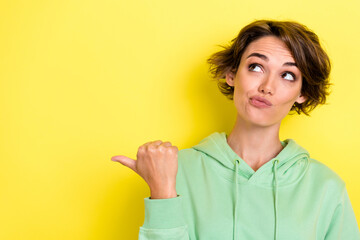 Photo portrait of lovely young woman look skeptical point empty space news dressed stylish green outfit isolated on yellow color background - obrazy, fototapety, plakaty