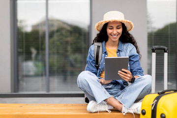 Cheerful lady traveller waiting for flight, using digital tablet