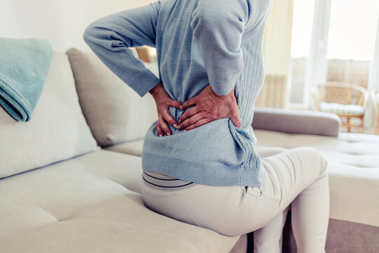 Cropped Image Of Senior Woman Suffering From Backache In Morning Sitting On Bed, Free Space. Lower Back Pain In Elderly Person.