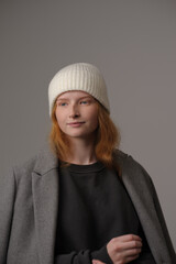 young girl model in white cap and gray coat isolated on grey background. Product photo mockup for fashion brands and marketplaces.