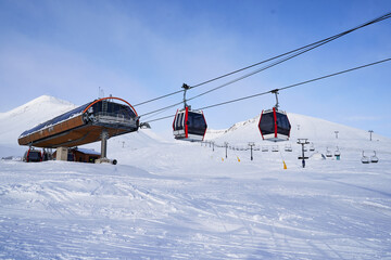 Cable car gondola at ski resort with snowy mountains on background. Modern ski lift with funitels...