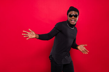 Portrait of attractive cheerful funky guy wearing black look having fun moving isolated over bright red color background