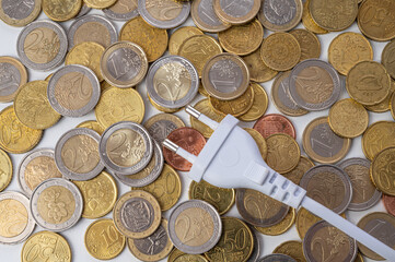 White electric plug, placed on a background of Euro coins. Increase in electricity bills, increases...