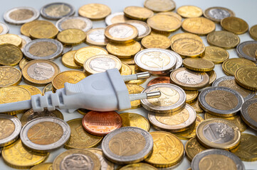 White electric plug, placed on a background of Euro coins. Increase in electricity bills, increases in electricity and energy costs.

