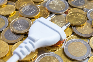 White electric plug, placed on a background of Euro coins. Increase in electricity bills, increases...