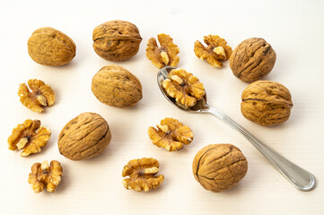 Teaspoon containing kernels, on a white cutting board, and beside walnuts.
