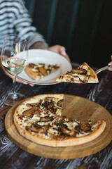 Mushroom pizza on a wooden board. Serving pizza. The chef cuts the pizza. A piece of pizza on a spatula.