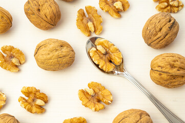 Teaspoon containing kernels, on a white cutting board, and beside walnuts.
