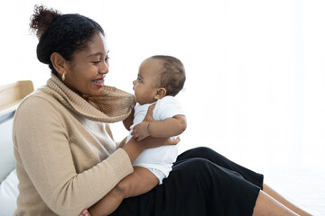Fototapeta premium close up African young mother carrying and playing with her adorable baby on bed