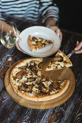 Mushroom pizza on a wooden board. Serving pizza. The chef cuts the pizza. A piece of pizza on a spatula.