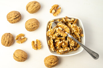 Walnuts in shell next to bowl containing shelled walnuts. Pruduction and consumption of nuts. Nutrition and properties of walnuts.
