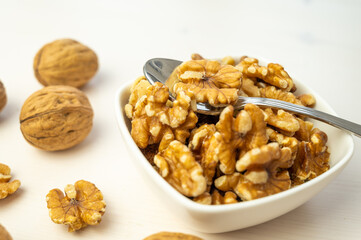 Walnuts in shell next to bowl containing shelled walnuts. Pruduction and consumption of nuts. Nutrition and properties of walnuts.
