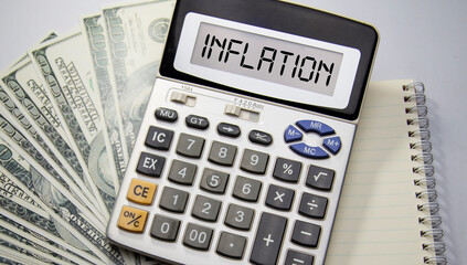 Inflation words in a calculator placed on a dollar and a notebook. Business concept. Inflation.