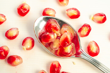 Pomegranate arils in bowl and spoon beside.
