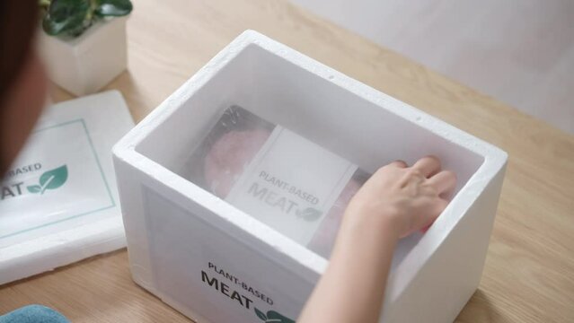 Close up people Gen Z woman happy unbox unpack open beyond meat box at home order buy zero beef plant based soy bean meal. Raw patty frozen cutlet clean food send from vegan diet retail eco store.