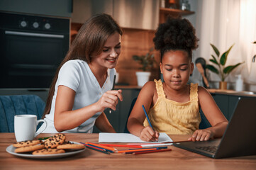 Learning how to draw. Young mother with her daughter is together at apartment