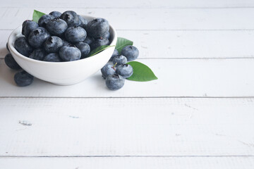 blueberry in a small white cup on a wooden table