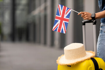 Woman with straw hat on luggage holding flag of UK