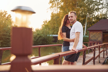 Happy wife and husband is outdoors on the wooden bridge at sunny day