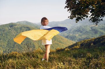 Little girl is holding Ukraine flag on the Carpathian Mountains
