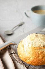 A cup of coffee and a loaf of bread with a brown napkin on grey background. 