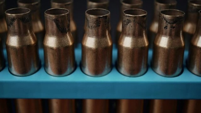Slow motion footage of empty bullet cases. Bullet shells in a blue container in three rows. 