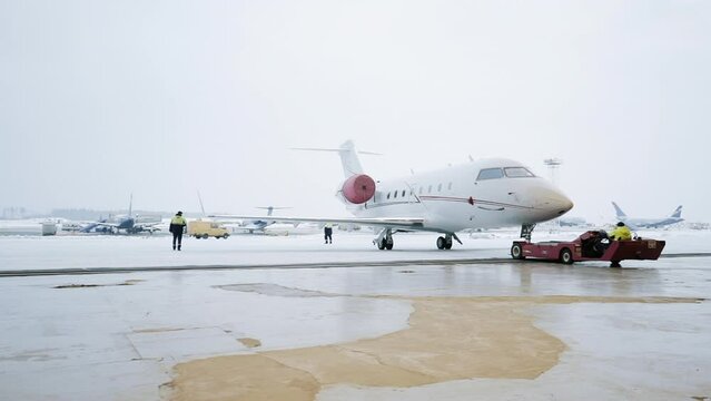 A small plane leaves the hangar. Business jet getting ready to take off. Winter view. High quality FullHD footage
