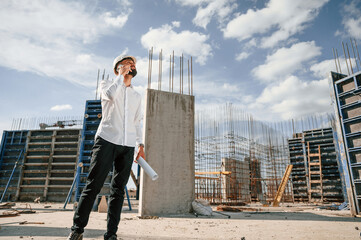 Having conversation by the phone. Man in uniform is working on the construction site