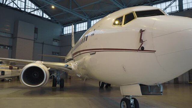Close up Shot of a Brand New Airplane Standing in a Aircraft Maintenance Hangar. Business plane jet on parking. High quality FullHD footage
