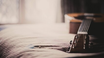 Selective focus of a guitar lying on bed