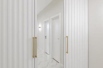 a white wardrobe with a mirror in the hallway