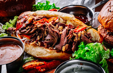 Philly cheese steak sandwich with meat, vegetables, cheese and sause on wooden table. street food