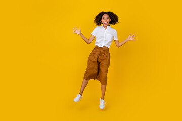 Fototapeta na wymiar Full size photo of overjoyed energetic lady jump raise hands good mood isolated on yellow color background