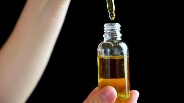 Natural oil for the care of eyelashes, eyebrows, facial skin drips into a glass jar of pipette