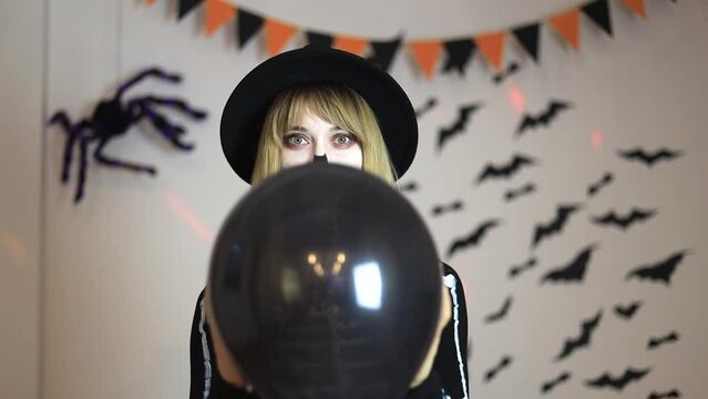 Young woman in a skeleton costume at a Halloween party holding a black balloon in her hands