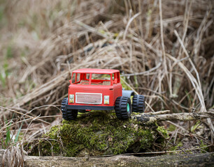 Ein altes rotes Spielzeugauto eines Kindes steht in einem Garten.