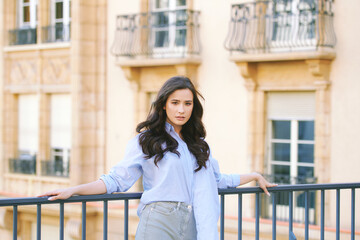 Fashion portrait of beautiful young woman, wearing blue shirt, posing outdoors