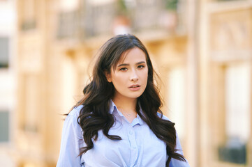 Fashion portrait of beautiful young woman, wearing blue shirt, posing outdoors