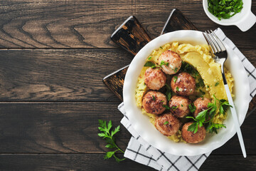 Swedish meatballs in cream sauce, potatoes and lingonberry sauce in bowl on old wooden rustic backgrounds. Swedish cuisine. Delicious creamy mashed potatoes. Top view.