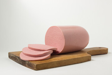 Boiled sausage on a wooden board on a white background. Sliced boiled sausage.