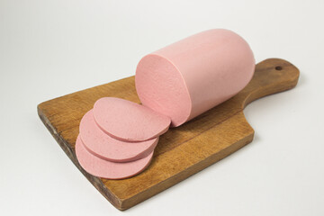 Boiled sausage on a wooden board on a white background. Sliced boiled sausage.