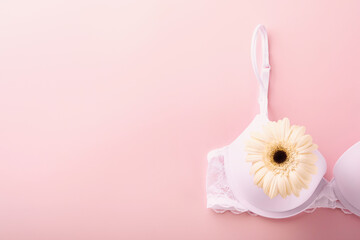 Breast Cancer Awareness Ribbon. White and red bra, gerberas with pink ribbon tape lying on female bra on backgrounds. Breast cancer awareness and October Pink day, world cancer day. Top view. Mock up